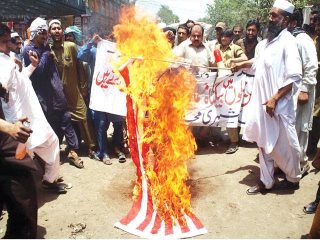 MULTAN: Activists of Muttahida Shahri Mahaz burning the US flag during a demonstration at Vehari Chowk on Wednesday.–Online