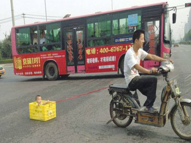 Chinese biker pulls tot in drinks crate 