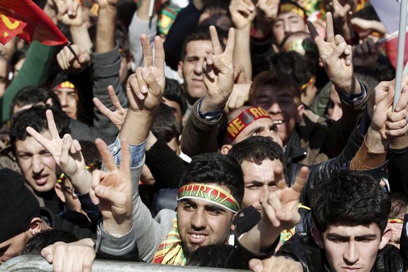People gesture while others wave Kurdish flags during a gathering celebrating in Turkey