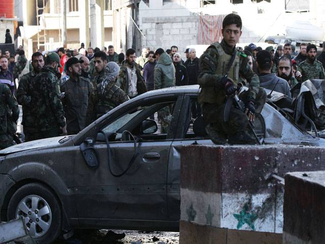 Syrian pro-government forces and residents gather at the site of suicide bombings in Syria