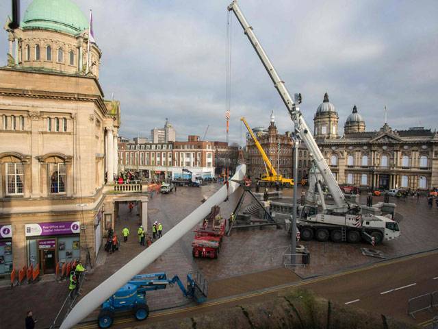 Workers manoeuvre the 'Blade' installation, a 75 metre-long hand-made fibreglass in UK