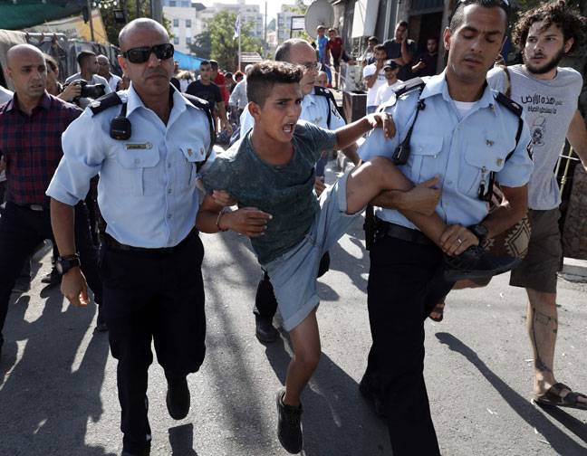 Israeli policemen detain a Palestinian boy during a protest