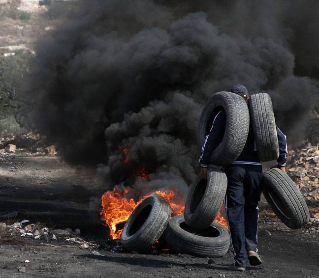 Palestinian demonstrators carries tires to burn clashes with Israeli forces