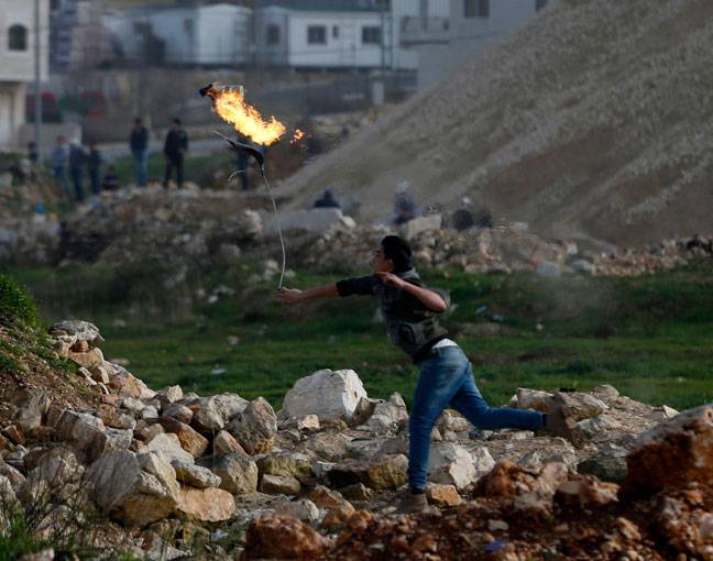 A Palestinian demonstrator throws a petrol bomb